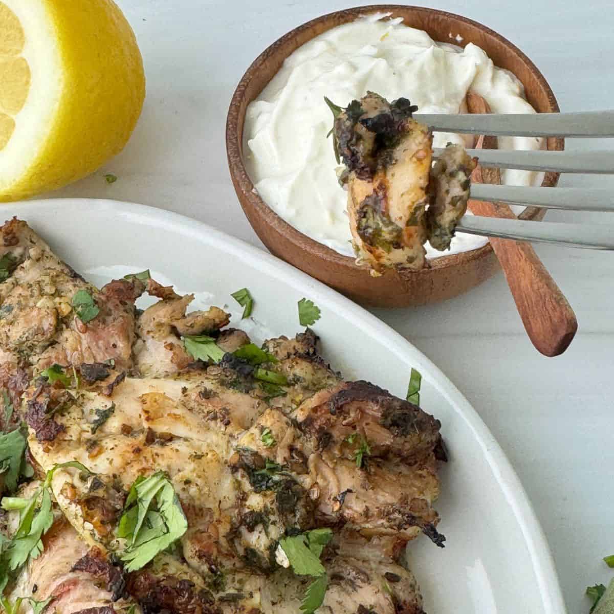 Showing a piece of the chicken on the end of a fork.
