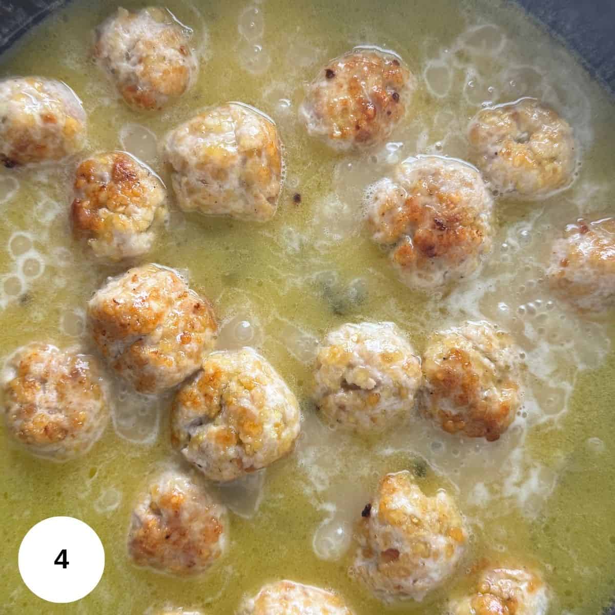 Cooking the meatballs in the sauce.