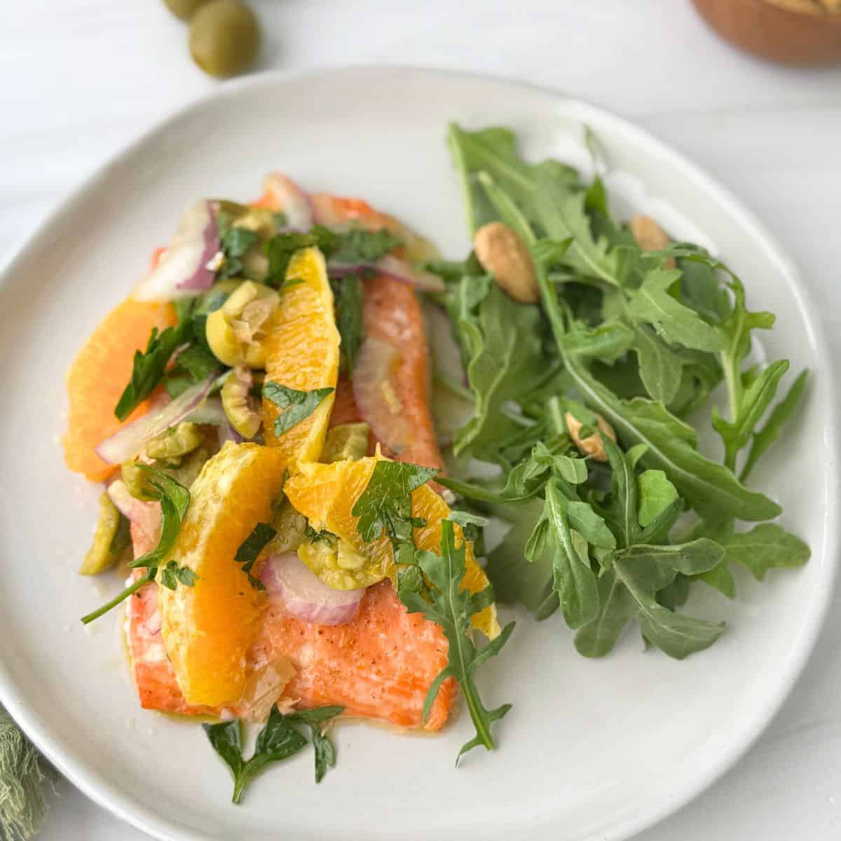 Salmon with a Citrus relish on a white plate.