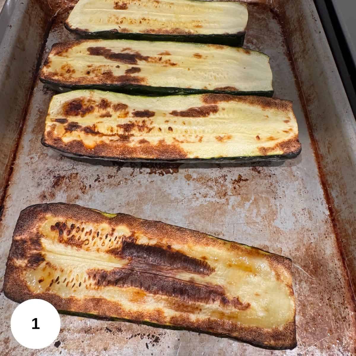 Broiled zucchini that is golden brown on a sheet pan.
