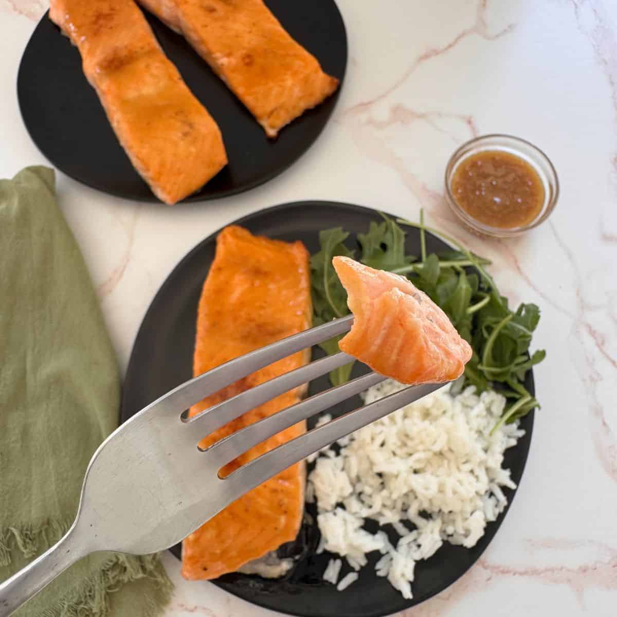 Holding a fork of salmon over the plate.
