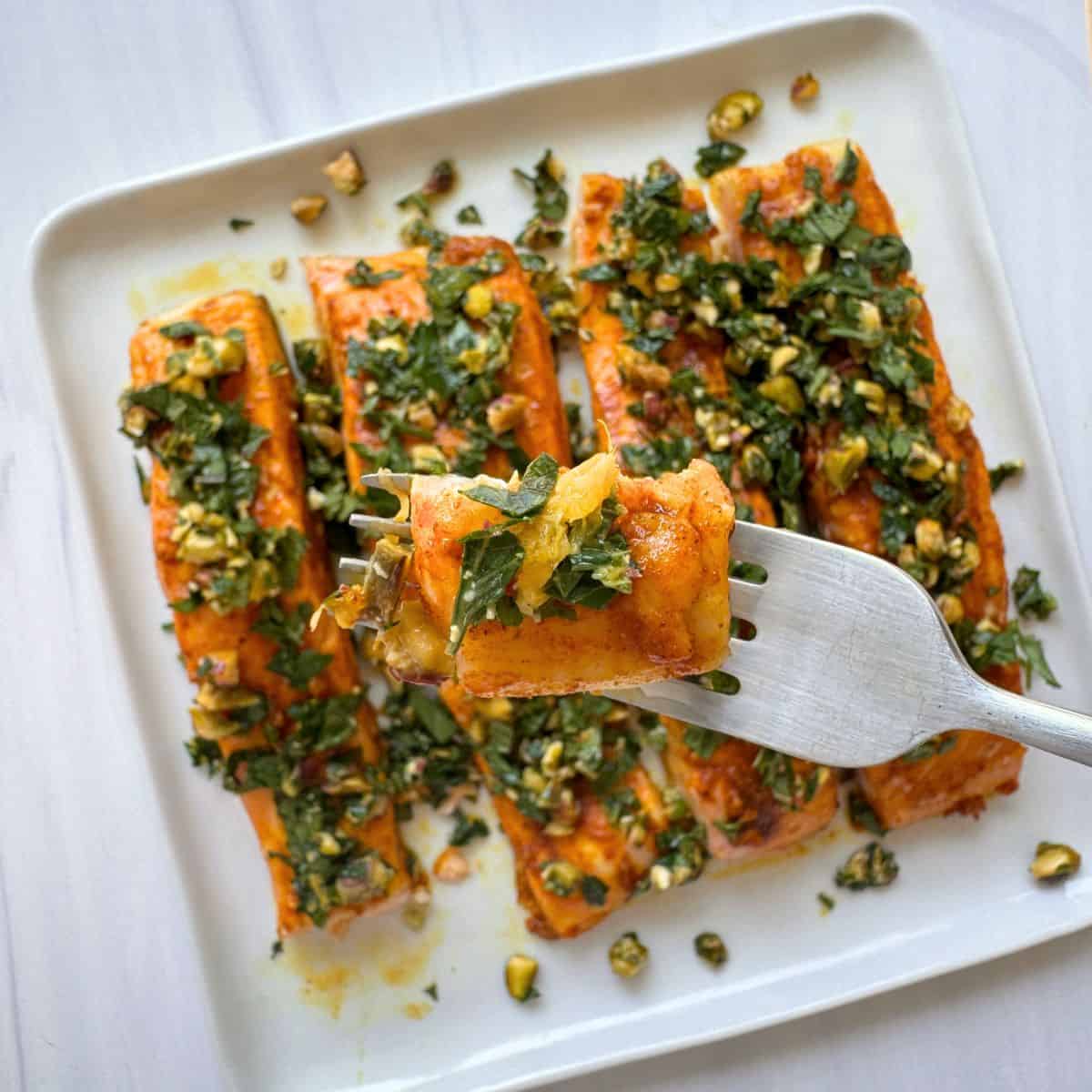 Holding a fork filled with the salmon and showing it up close. 