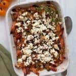 A casserole dish with Mediterranean Greek Shrimp topped with feta cheese and baked.