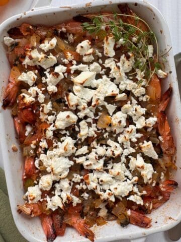 A casserole dish with Mediterranean Greek Shrimp topped with feta cheese and baked.
