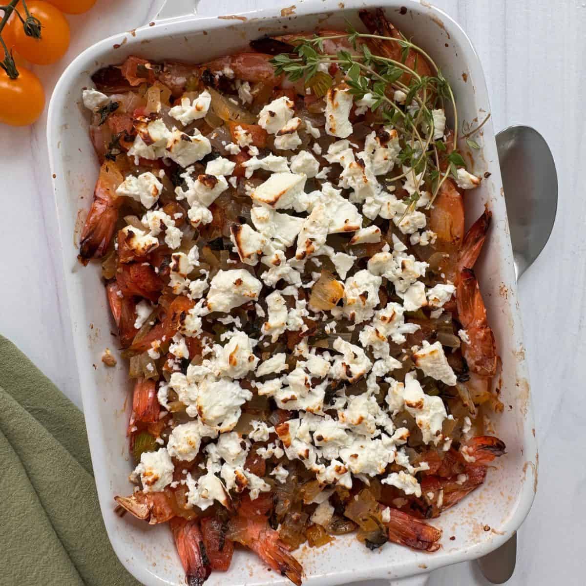 A casserole dish with Mediterranean Greek Shrimp topped with feta cheese and baked. 