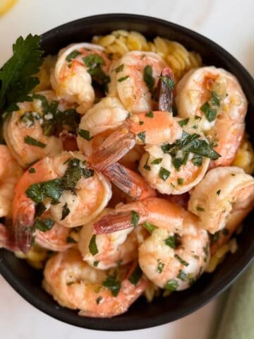 Shrimp Scampi in a black bowl with a green napkin next to it.