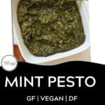 A white bowl filled with vibrant mint pesto, garnished with a fresh mint leaf, sits on a white surface. Text below reads: MINT PESTO, GF | VEGAN | DF, DOWNLOAD NOW.