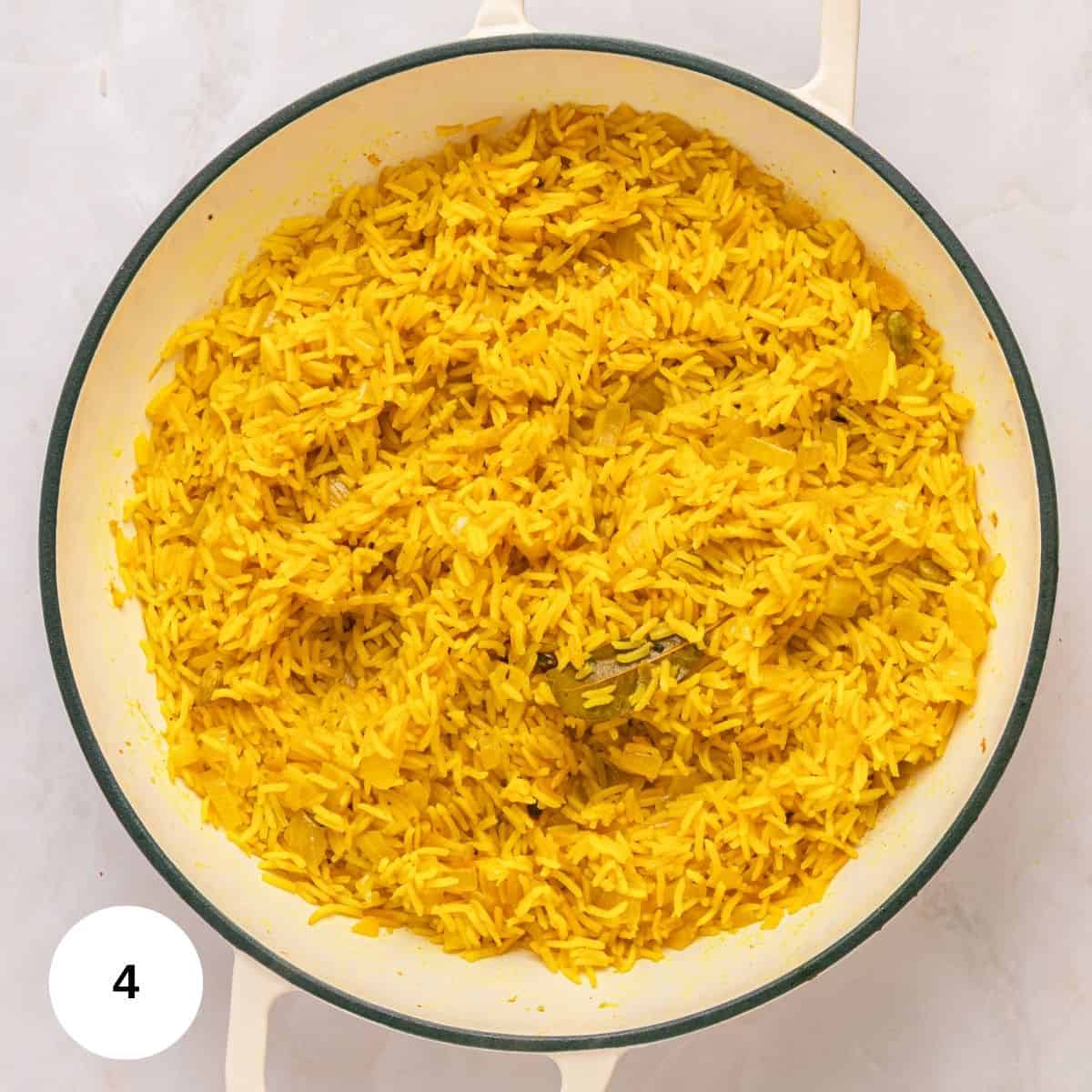 A white pan filled with fluffy, well-seasoned Mediterranean Rice sits on a light surface. The yellow rice, infused with turmeric and visible spices, looks delicious. A white circle with the number 4 is in the bottom left corner.