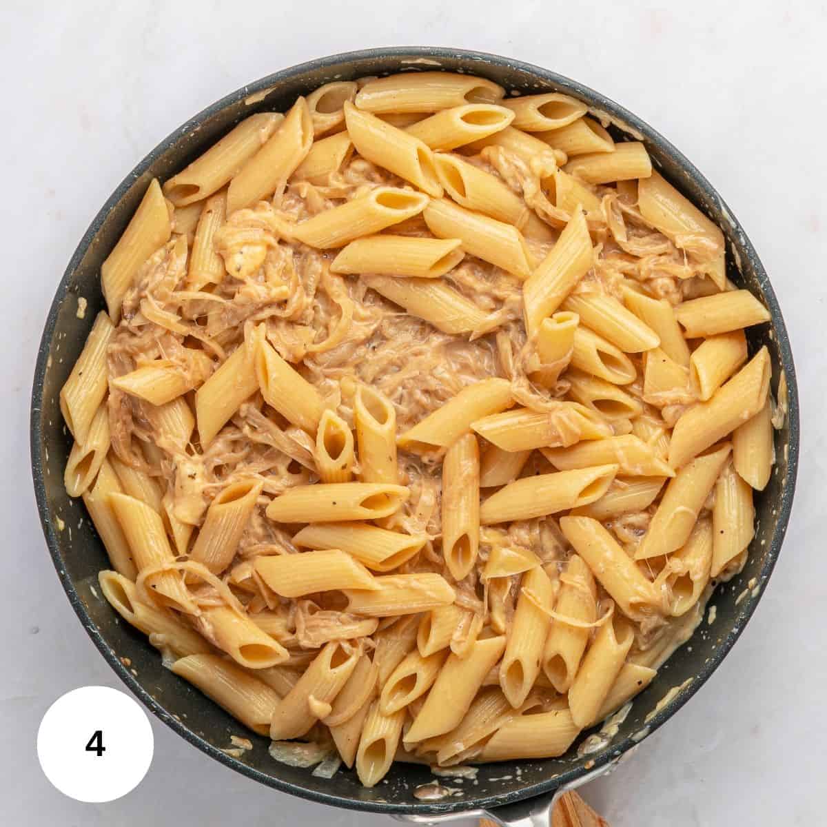A skillet filled with penne pasta tossed in a creamy, light-colored sauce with shredded chicken and melted Gruyère. The number 4 appears in a white circle in the bottom left corner.