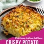 A slice of golden-brown crispy potato kugel casserole on a gray plate garnished with fresh herbs, with bowls of greens and chopped herbs in the background. Text reads: Crispy Potato Kugel Casserole with onions, scallions, and thyme.