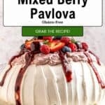 A berry pavlova dessert topped with whipped cream, mixed berries, and berry sauce sits on a white cake stand. The image features text promoting a quick and easy gluten-free berry pavlova recipe.