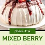 A berry pavlova dessert topped with whipped cream, strawberry sauce, and fresh berries sits on a cake stand. Text reads Gluten-Free Mixed Berry Pavlova with a logo at the bottom.