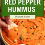 A hand dips pita bread into a bowl of Roasted Red Bell Pepper Hummus, garnished with chickpeas and herbs. Text overlay reads Smoky & Creamy Hummus. Grab the recipe! Tried. Tested. Never AI.