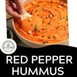A hand dips a pita chip into smoky hummus, topped with chickpeas, parsley, and paprika. Text below reads Roasted Red Bell Pepper Hummus: Smoky & Creamy. Download Now.