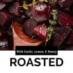 Close-up of roasted beet chunks garnished with thyme on a wooden spoon. Text on image reads: With Garlic, Lemon, & Honey. Flavorful roasted beets.