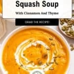 A bowl of warm spice carrot and butternut squash soup topped with a swirl of cream, thyme, and pumpkin seeds.