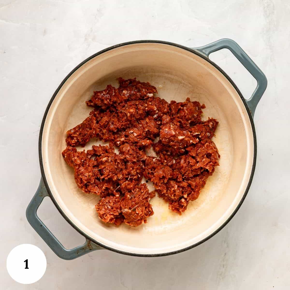 Raw ground meat browning in a dutch oven for Tuscan Tortellini Soup.