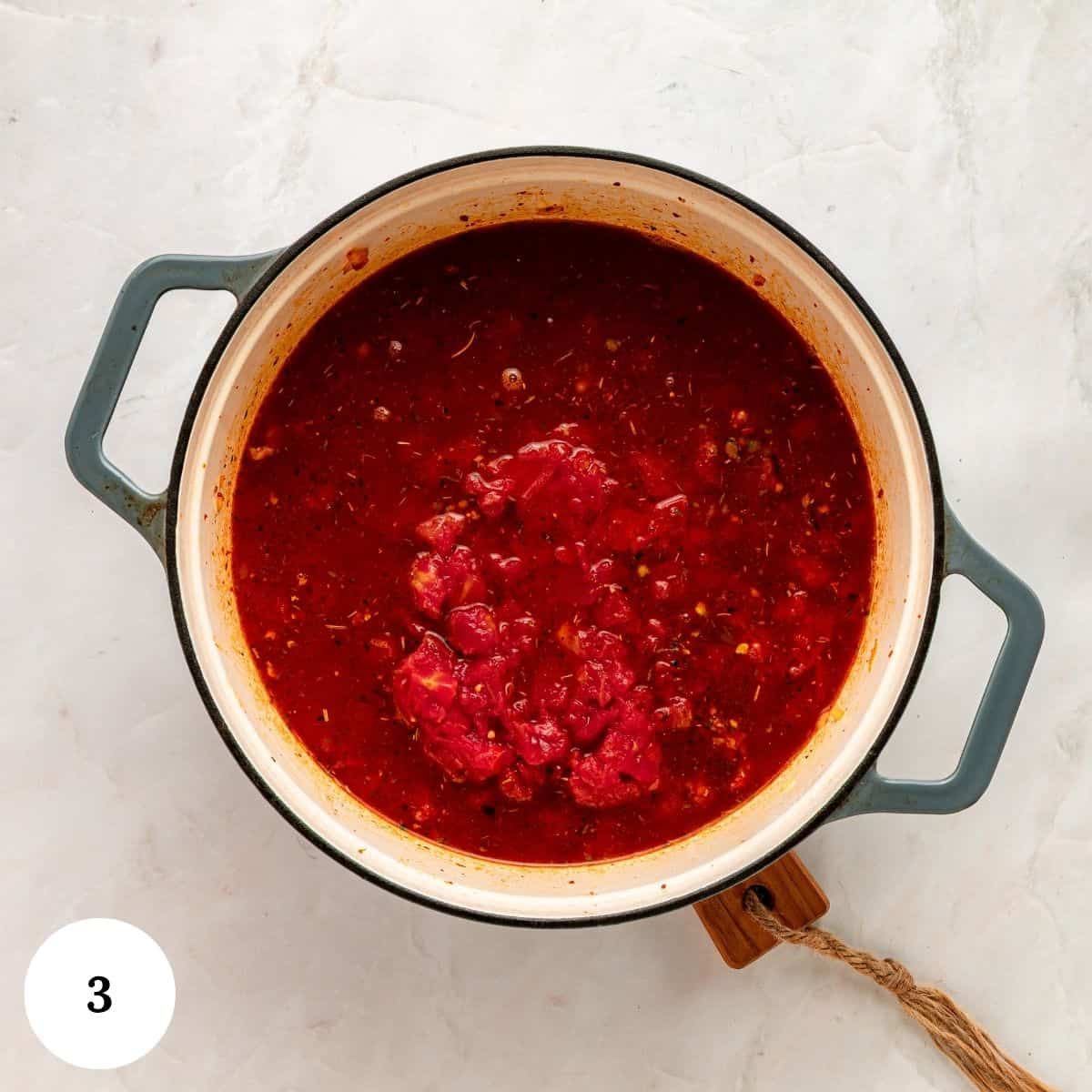 Tomato sauce for a Tuscan Tortellini Soup simmering in a Dutch oven.