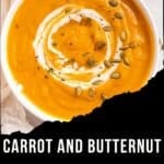 A bowl of warm spice carrot and butternut squash soup, swirled with cream and topped with pumpkin seeds.